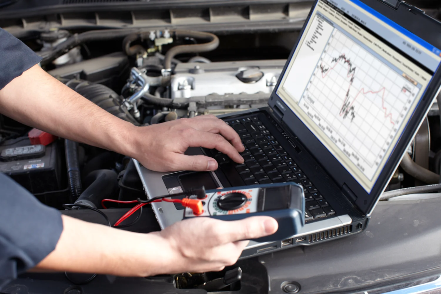 Mechanic running computerised diagnostics on a vehicle engine