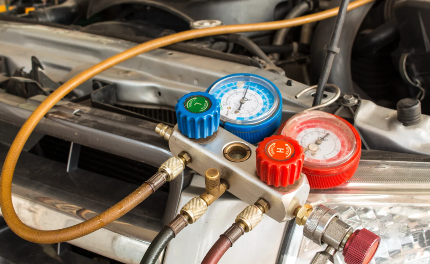 Car air conditioning re-gas equipment connected to an engine bay